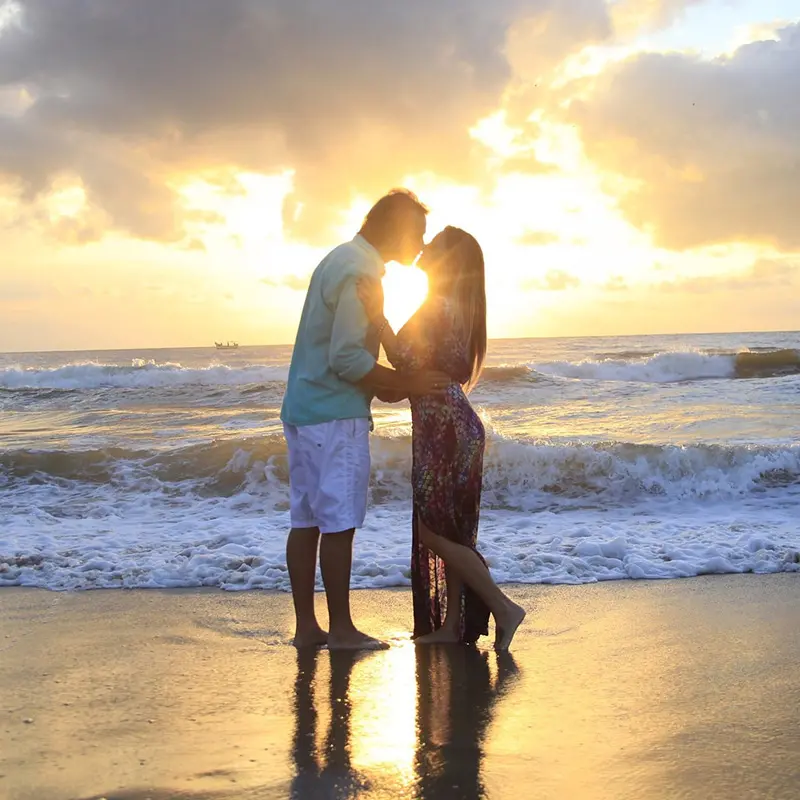 Couple qui s'embrasse avec un couché de soleil en bord de mer